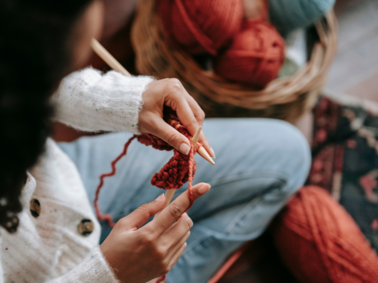 A woman knitting something with red yarn.