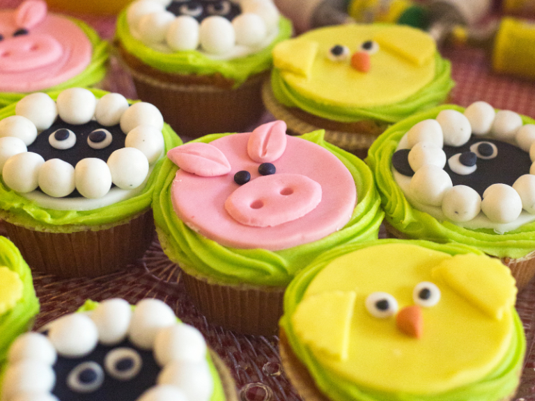 Cupcakes decorated like pigs, sheep and baby chicks.